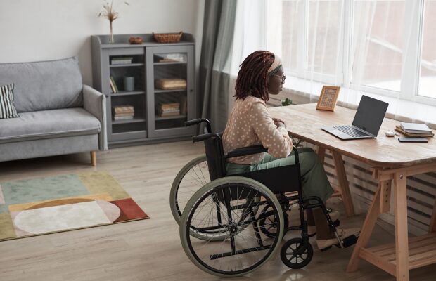 girl in a wheelchair at home looking at her laptop