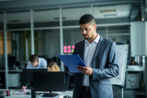 Man in office environment looking at a clipboard