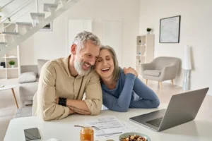 Happy senior couple laughing while managing finances online.