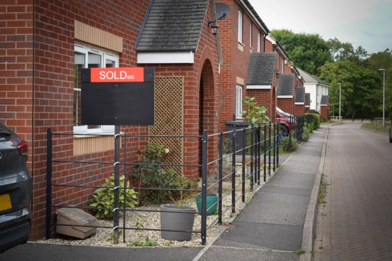 A Sold STC sign in front of a row of modern red-brick houses